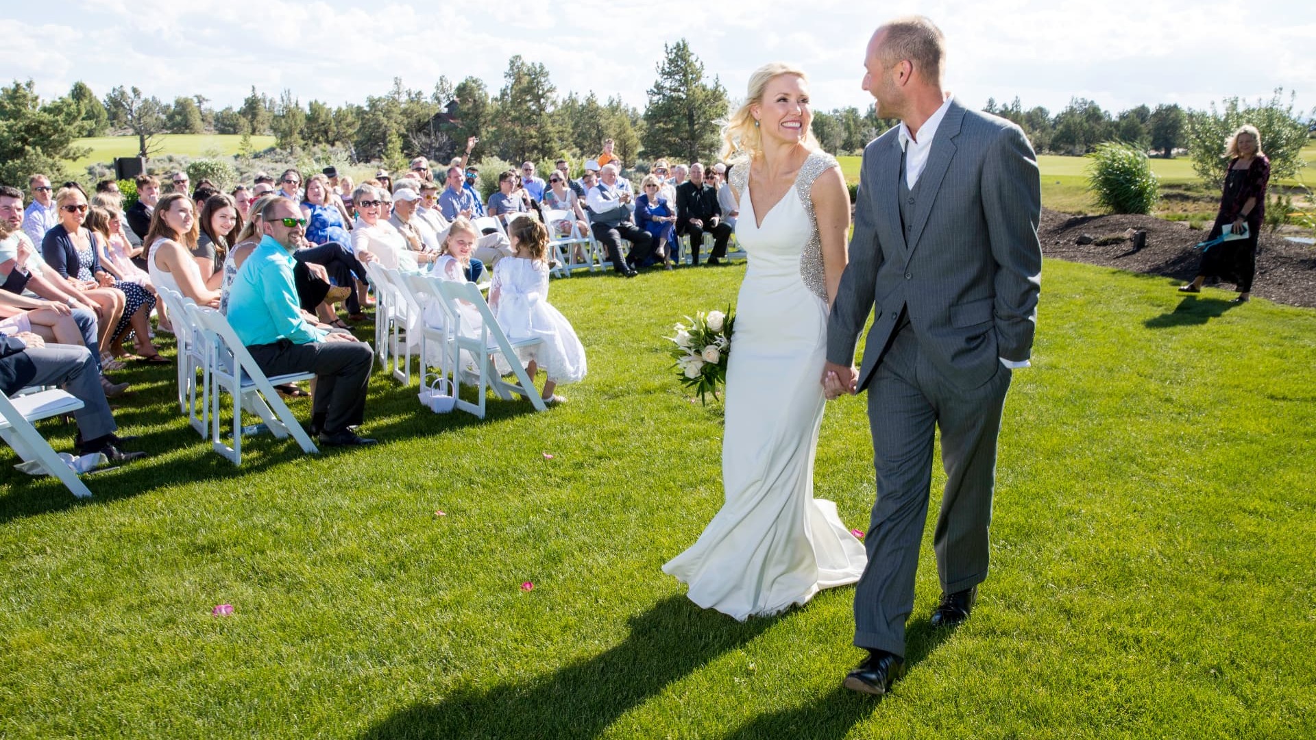 A bride and groom walking hand in hand down the aisle after their outdoor ceremony